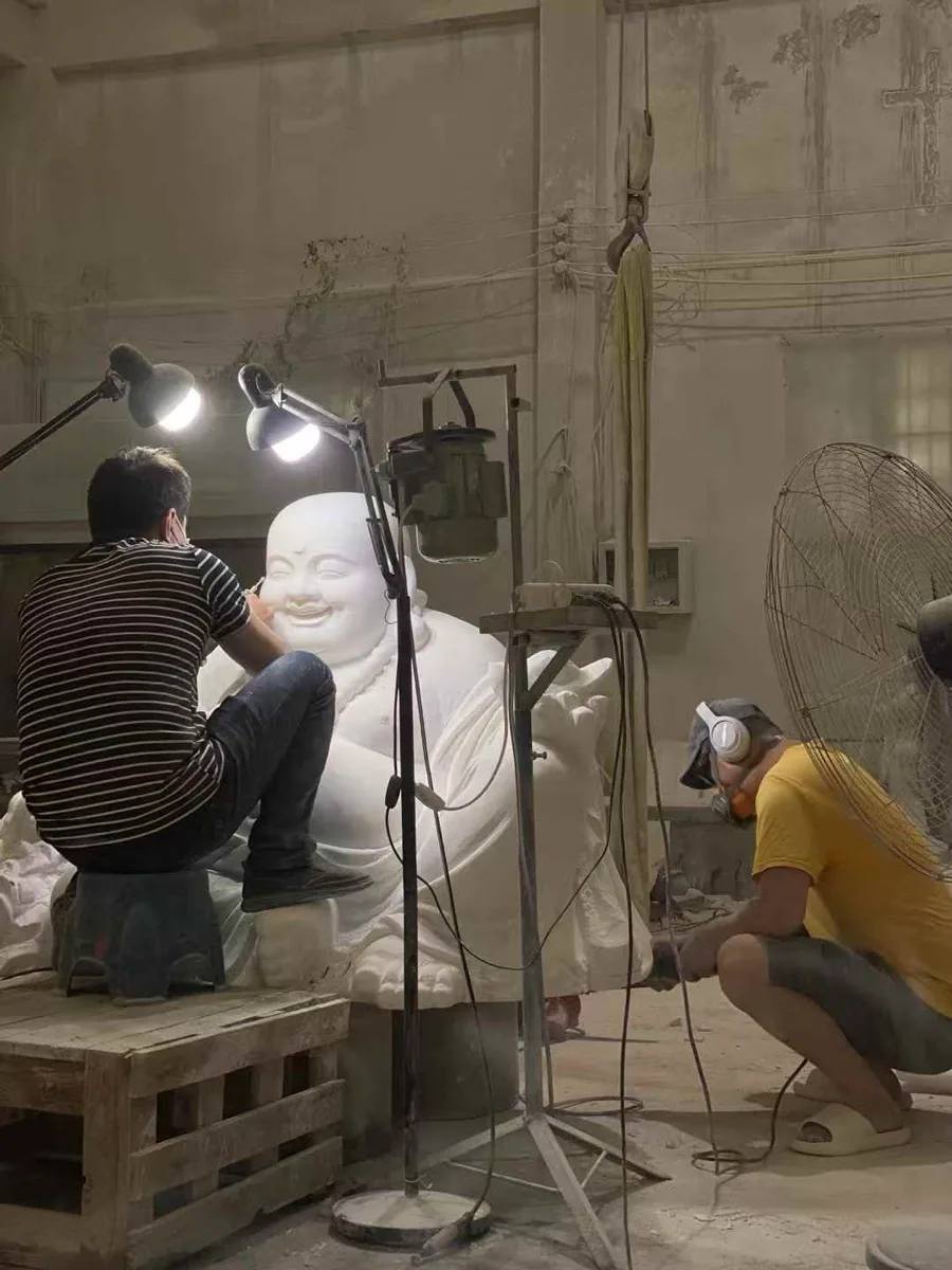 Two carvers at work on a large figure — Huian, Quanzhou